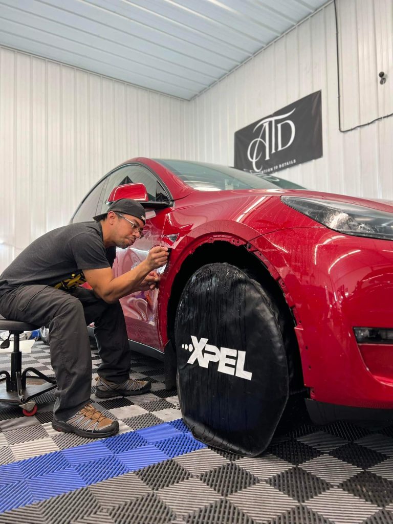 XPEL certified installer applying PPF to red Tesla at Attention To Details